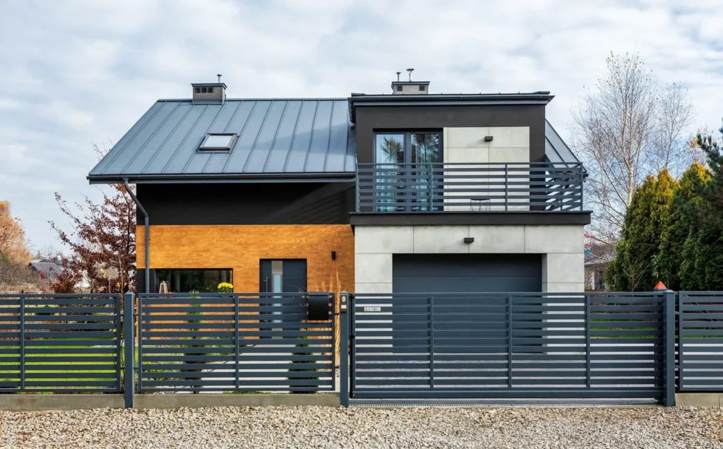 Dom z bramą WIŚNIOWSKI UniTherm widziany zza ogrodzenia